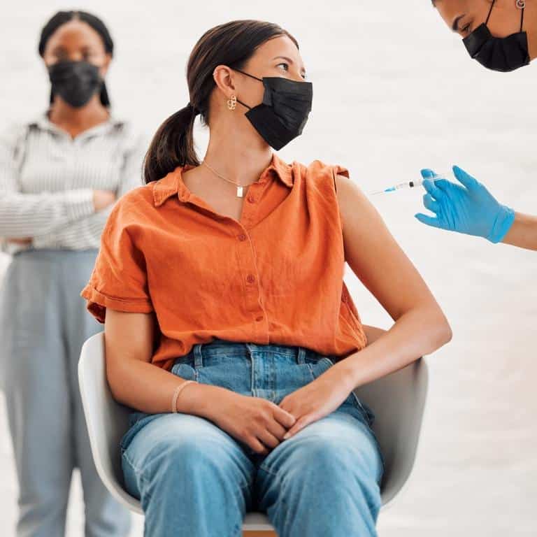 Doctor Giving An Injection At An Onsite Flu Clinic To A Woman
