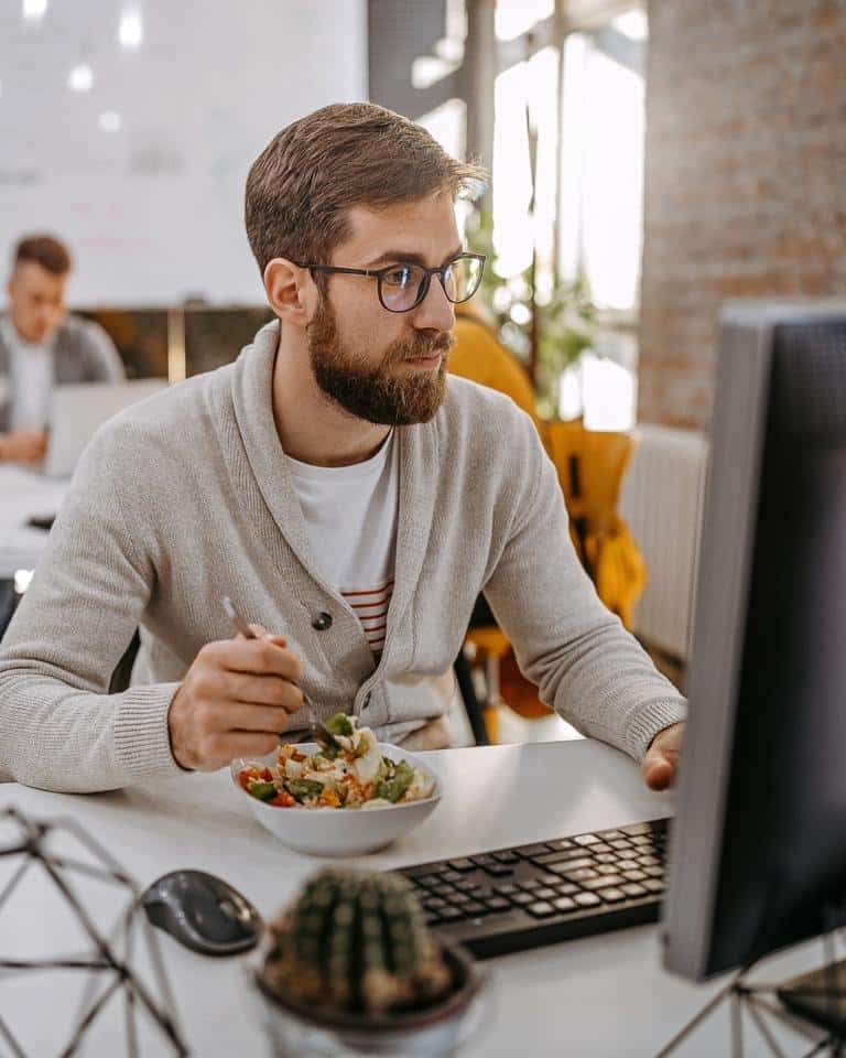 A Man With Glasses Enjoying A Salad While Working For Gut Health