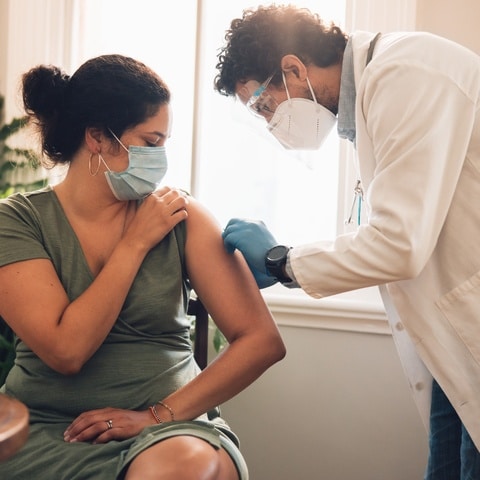 A Doctor Giving Onsite Flu Shots To A Woman At A Clinic
