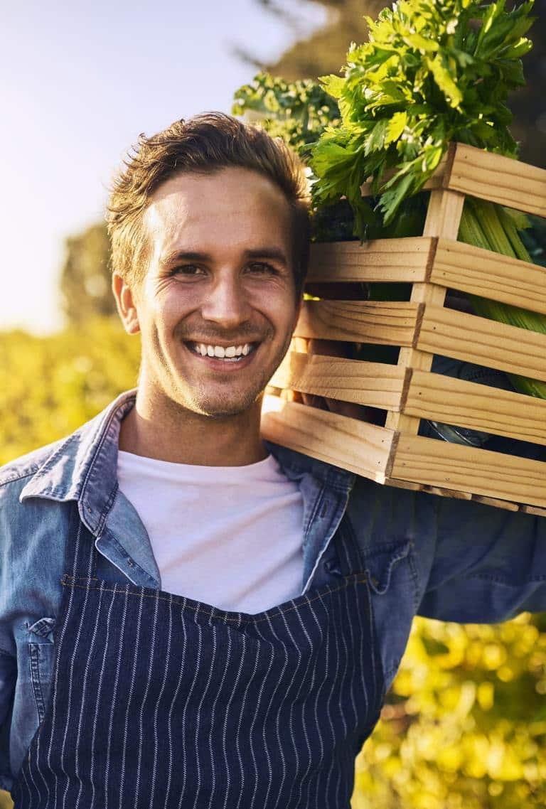 Smiling Man With A Crate Of Fresh Vegetables Highlighting Food Sensitivity