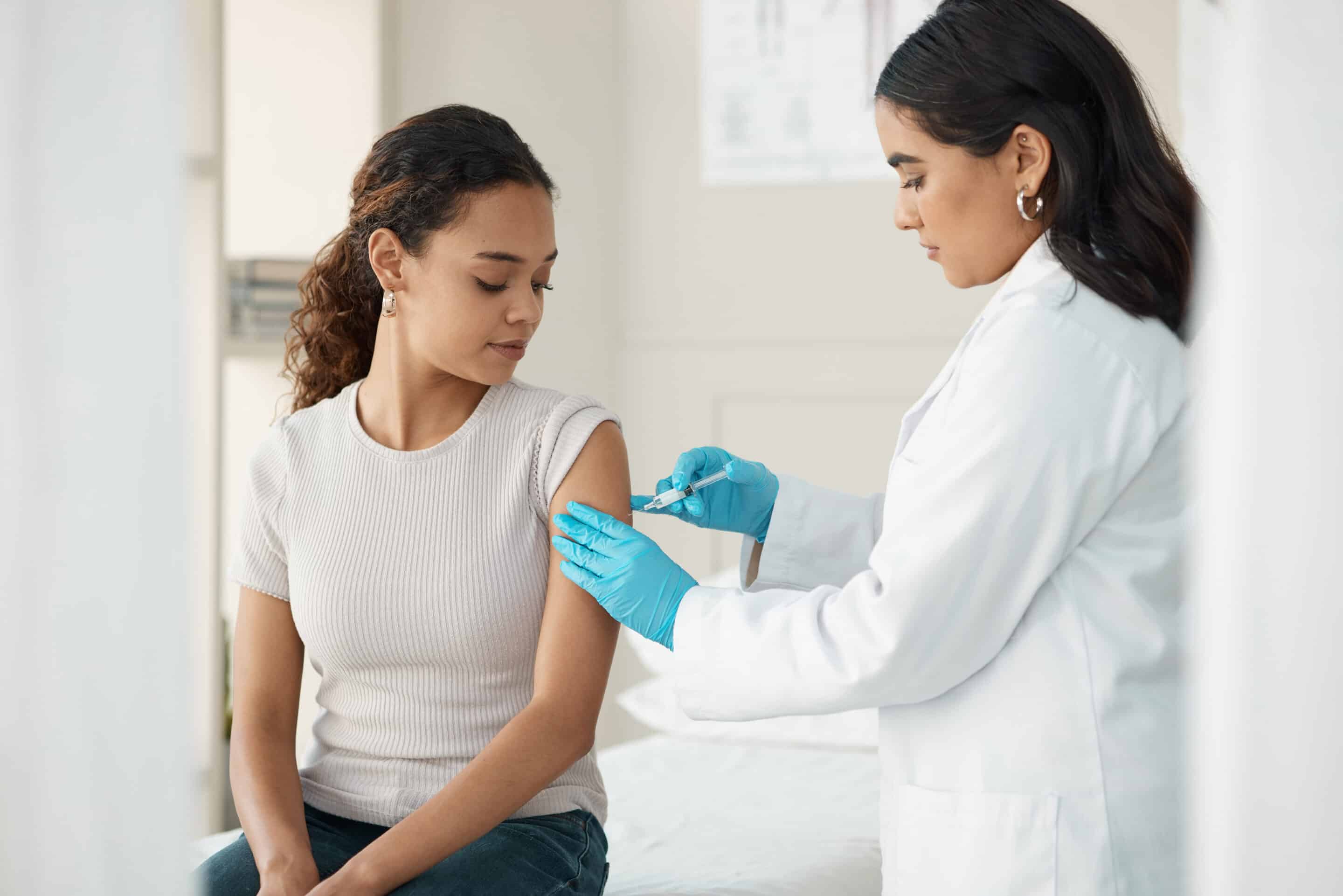 Nurse adminstering workplace flu shots to a female employee.